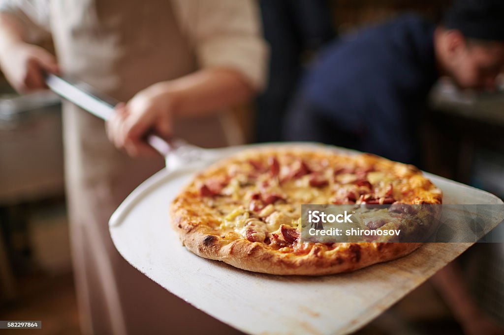 Italian pizza Traditional pizza being taken out of oven Pizzeria Stock Photo