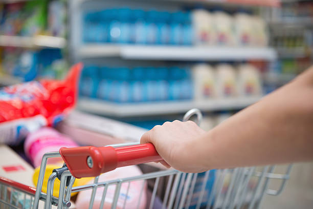 lady shopping with a full filled cart in a supermarket stock photo