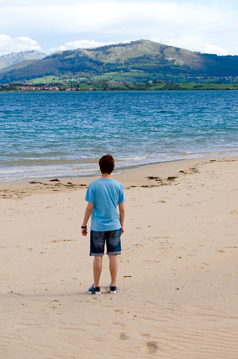 Young adult admiring the landscape at a beach in Santander, Spain.
