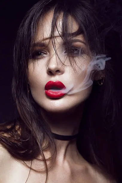 Photo of Beautiful sexy brunette girl with bright makeup, red lips, smoke