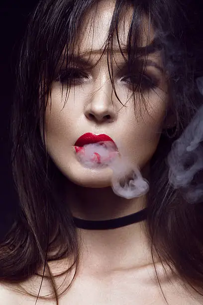 Photo of Beautiful sexy brunette girl with bright makeup, red lips, smoke