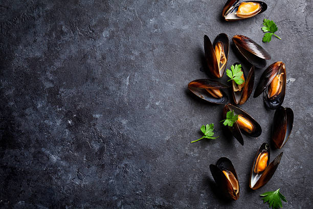 Mussels and parsley Mussels on stone table. Top view with copy space mussel stock pictures, royalty-free photos & images