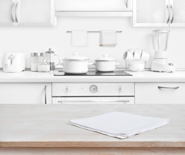 Wooden table with towel on blurred white modern kitchen background