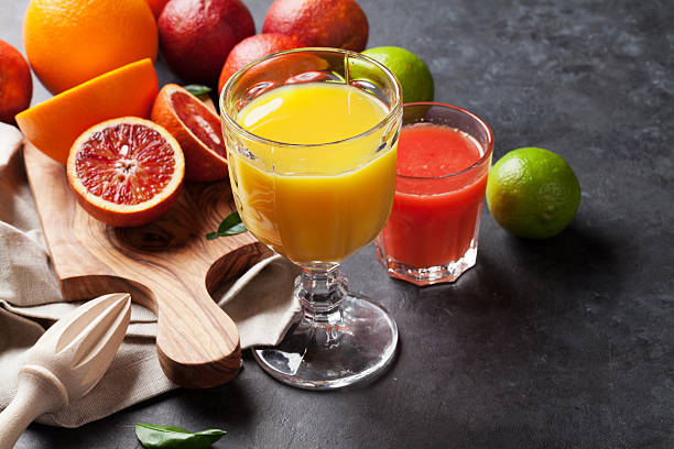 Fresh citruses and juice Fresh citruses and juice on dark stone background. Oranges and limes fruit juice stock pictures, royalty-free photos & images