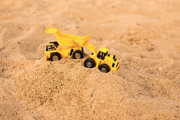 istock yellow excavator and dumper working in the sand quarry 582305388