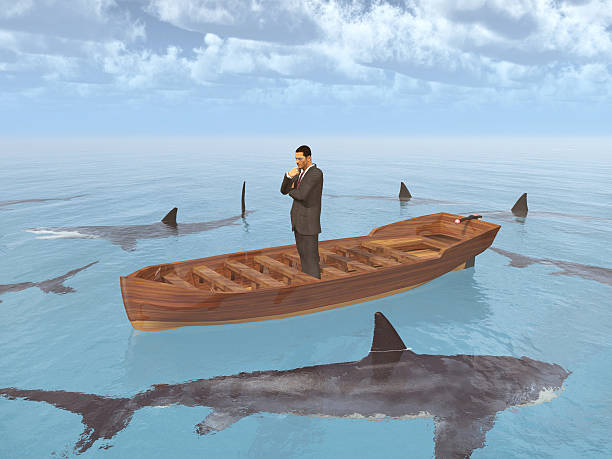 istock Businessman in a boat surrounded by sharks 582308122