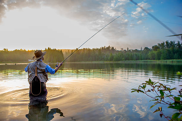 young man flyfishing at sunrise - sporting fisherman fishing recreational pursuit imagens e fotografias de stock