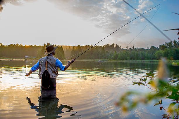 młody człowiek flyfishing o wschodzie słońca - fisherman stream fly fishing fishing zdjęcia i obrazy z banku zdjęć