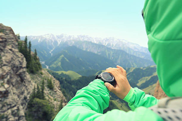 wanderer, der den altimeter auf der sportwache am berggipfel überprüft - checking the time watch women looking stock-fotos und bilder