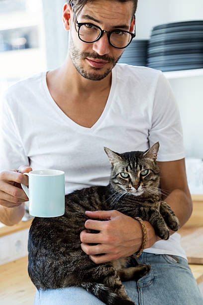 istock Handsome young man playing with cat in the kitchen. 582312982