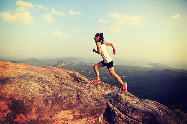 young asian woman runner running on mountain peak