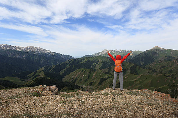 istock cheering successful woman backpacker open arms on mountain peak 582315566