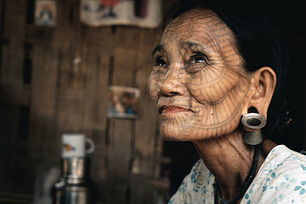 Portrait of old tattooed woman, Myanmar Kyee Chaung, Myanmar - May 30, 2016: Portrait of old woman with facial tattoos (Aung Sein, 73 years old) in Chin village. Village located near Lemro river and Mrauk U city. Face-tattooed women in Chin State is an indispensable part of Burma culture. Chin women were typically tattooed between the ages of 10 and 20. This continued until 1960. Now practice of facial tattoo is no longer permitted by the Burmese authorities. All tattooed women are old and this part of the Chin culture will soon be gone. tribals tattoos stock pictures, royalty-free photos & images