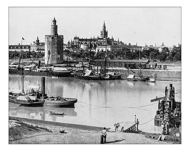 Antique photograph of view of Seville (Spain)-19th century Antique photograph of a glimpse of Siville (Spain), seen from the bank of the River Guadalquivir, in a 19th century picture depicting the city center (that hosts some  UNESCO World Heritage Sites) with the 15th century Gothic St. Mary of the See Cathedral, the 12th century Moorish Giralda tower (bell tower of the Seville Cathedral) and more on the foreground the Moorish dodecagonal military watchtower called Torre del Oro   seville port stock illustrations