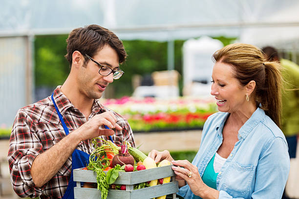 istock Young farmer talks about produce with customer 582317576