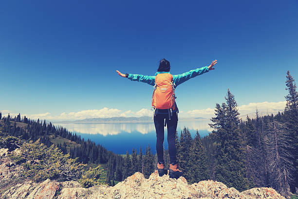 istock cheering successful woman backpacker open arms on mountain peak 582317600