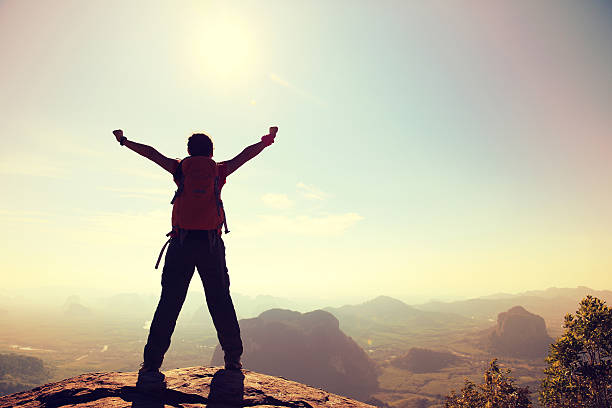 istock cheering woman hiker at sunrise mountain peak 582318992