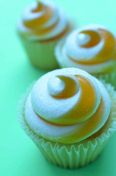 istock Three mango swirl cupcakes on green paper 583689448