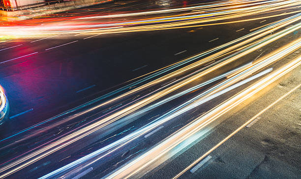 percorsi leggeri colorati a lunga esposizione attraverso l'incrocio stradale, traffico astratto - rush hour flash foto e immagini stock