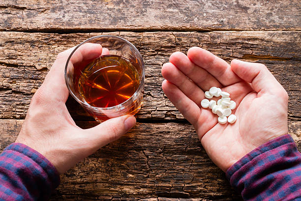 アルコールと丸薬のグラスを持っている男 - pill medicine capsule excess ストックフォトと画像