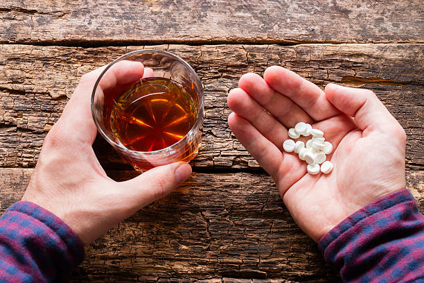 man holding a glass of alcohol and pills man holding a glass of alcohol and a handful of pills sleeping pill stock pictures, royalty-free photos & images