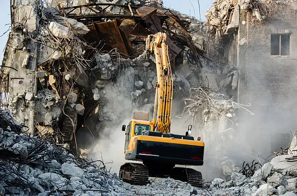 Photo of Excavator working at the demolition of an old industrial buildin