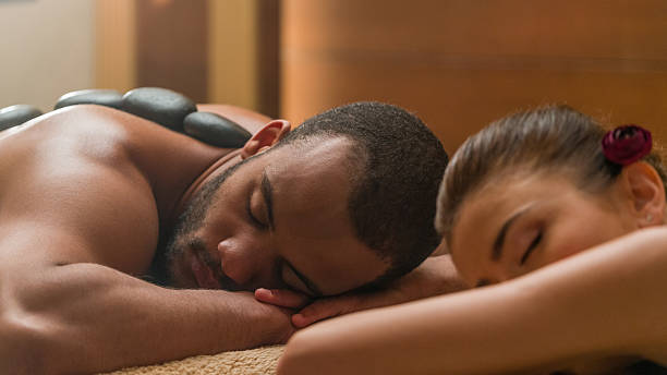 pareja joven en masaje - lastone therapy pampering spa treatment women fotografías e imágenes de stock