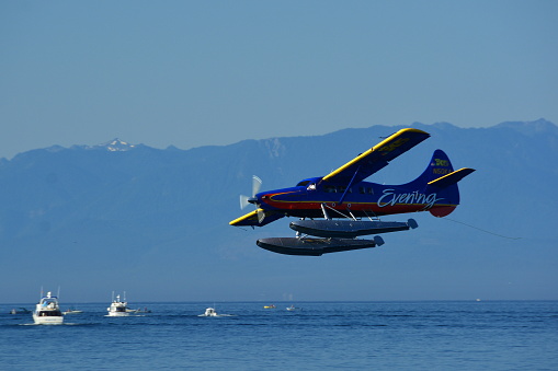 Victoria BC,Canada,August 4th 2014.Local fisherman on the water watch as a float plane comes in for a landing on its approach to Victoria's inner harbor.