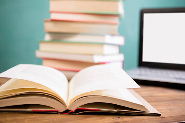 istock Books and laptop computer on school desk with chalkboard. 583708244