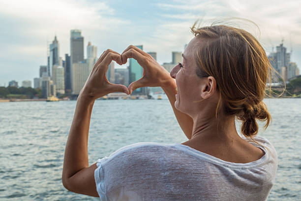istock Young woman in Sydney harbour makes heart shape finger frame 583709542
