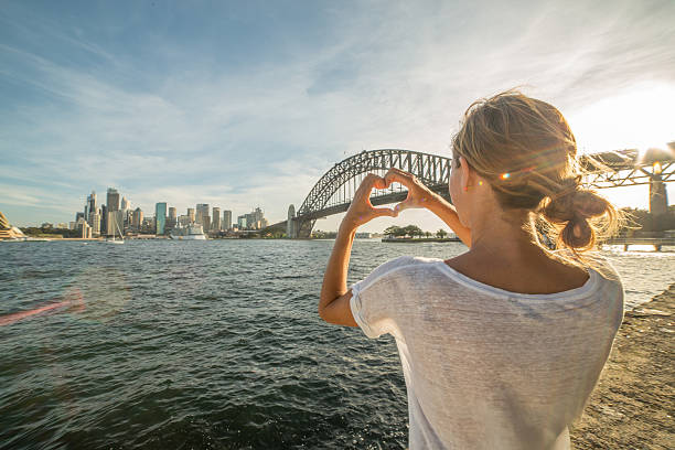istock Woman makes heart shape finger frame on Sydney skyline 583711086