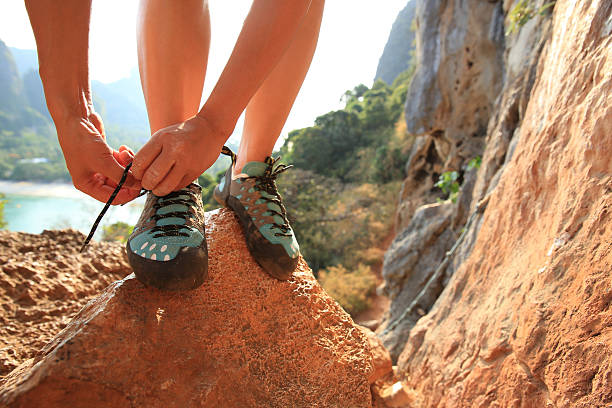 istock one young woman rock climber tying shoelace on rock 583713954