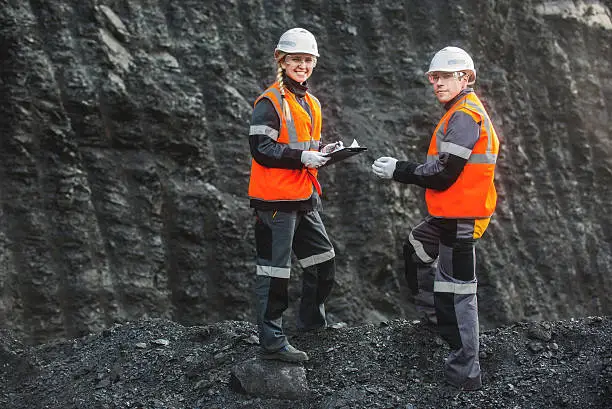 Two speacialists examining coal at an open pit