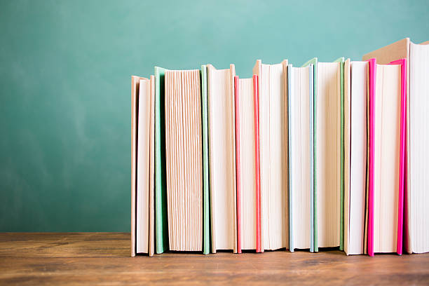 istock School books stacked on desk with chalkboard. 583716388