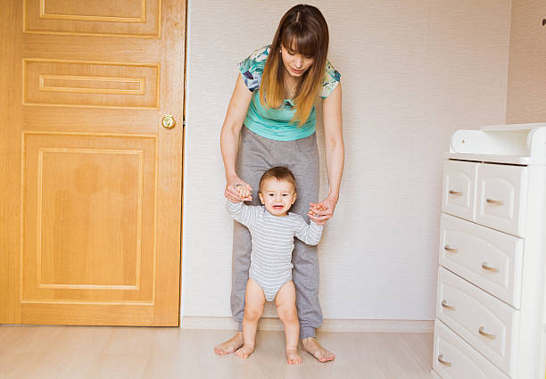 istock Mother teaching her cute little son to walk holding hands 583717832