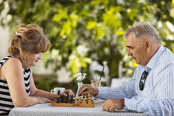 istock Side view of mature couple playing chess in their backyard. 583720774
