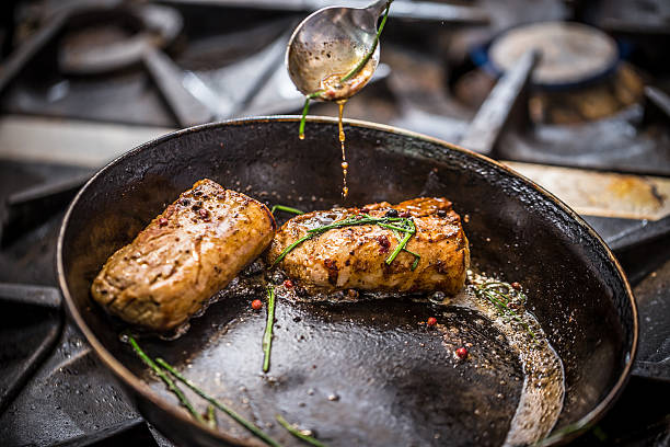 Chef prepares a meal Chef prepares a meal in a commercial restaurant kitchen braising pan stock pictures, royalty-free photos & images