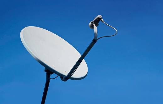 Rusty old white satellite dishes on blue sky background