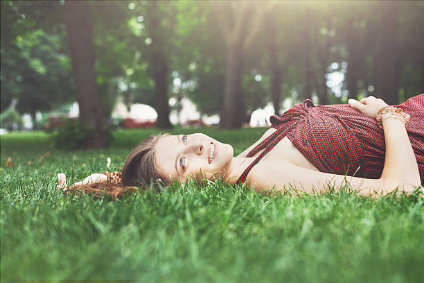 istock Beautiful young girl lying on grass in summer park 583726262