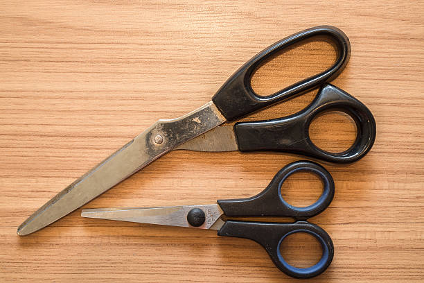 istock Old Black plastic scissor on wooden board 583727442