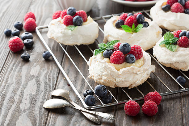 Pavlova cake with fresh summer berries Meringues Pavlova cakes with fresh raspberry and blueberry on dark rustic wooden background, selective focus pavlova stock pictures, royalty-free photos & images