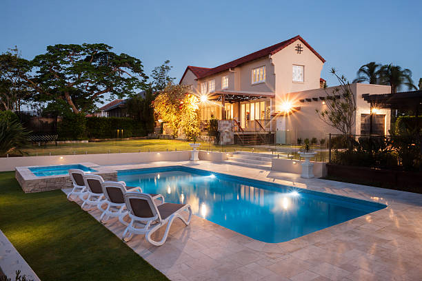 istock Modern pool with a large house illuminated with lights 583727974