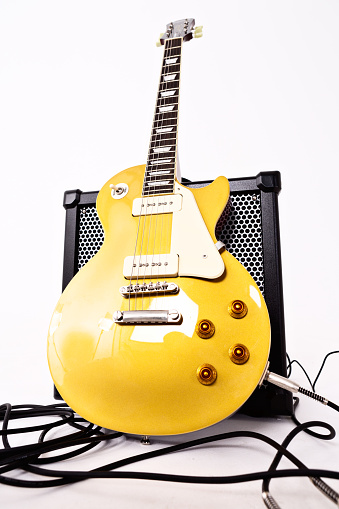 Cape Town, South Africa - July 2, 2016: Shot from a low angle, a distorted perspective view of a '56 Les Paul Pro electric guitar in goldtop finish, manufactured in 2014 by Epiphone, a brand of the US-based Gibson corporation. This instrument is an authentic, authorized reproduction of a 1956-vintage Gibson model, complete with a fat neck profile and  P-90 pickups   of the type originally fitted to the Les Paul before their replacement by humbuckers in the late 1950s. P-90 pickups are riding the modern retro wave and returning to favor among guitarists. The guitar is leaning against a Roland Cube 80 GX amplifier.