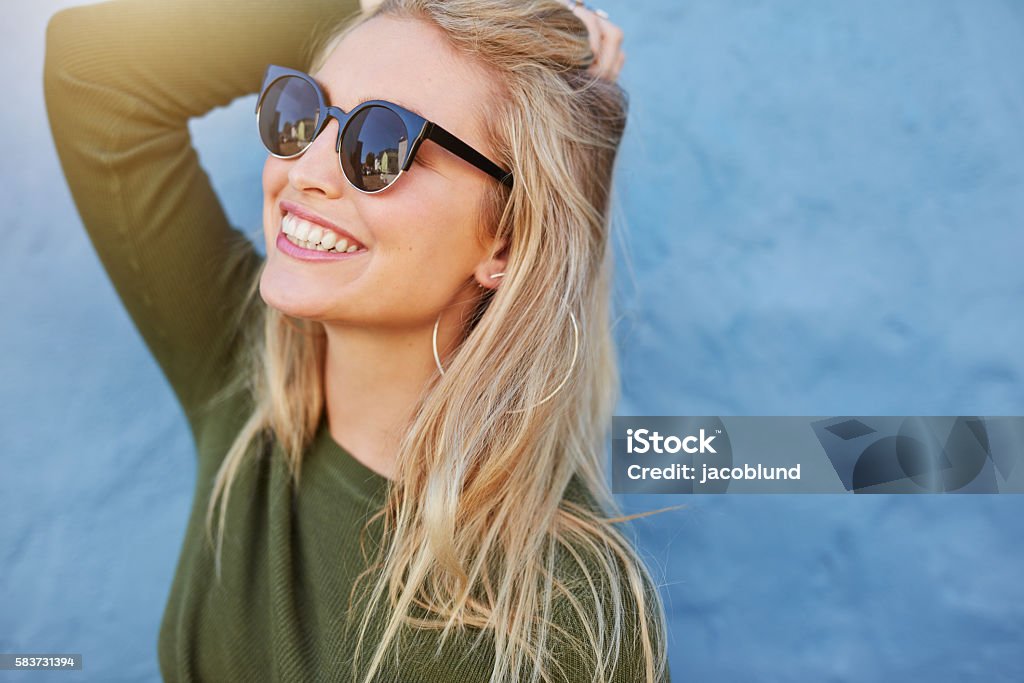 Cheerful young woman in sunglasses Cheerful young woman in sunglasses against blue background. Beautiful female model with long hair. Sunglasses Stock Photo