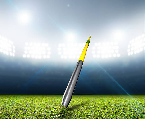 Javelin In Generic Floodlit Stadium A javelin pegged into the turf of a generic stadium with a green grass pitch at night under illuminated floodlights javelin stock pictures, royalty-free photos & images