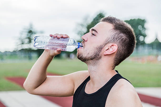 istock Athlete drinking water from transparent bottle on running track 583733820