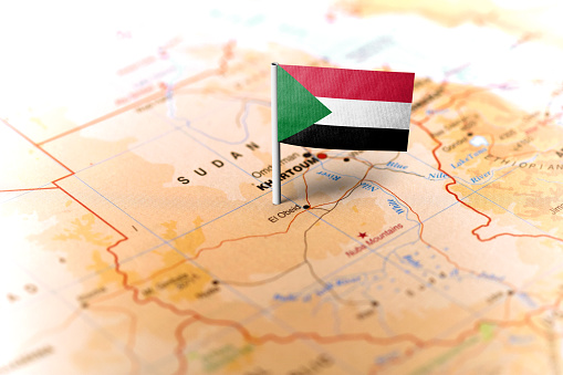 The flag of Sudan pinned on the map. Horizontal orientation. Macro photography.