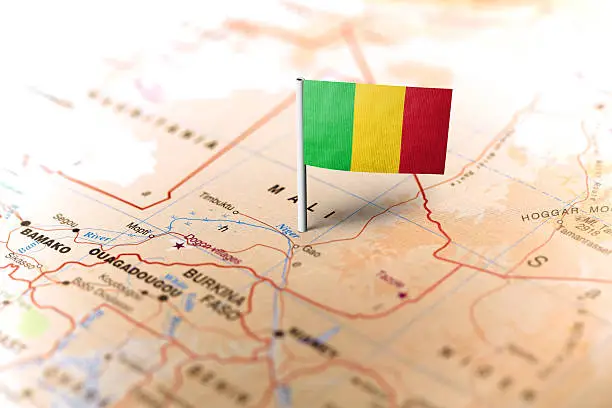 The flag of Mali pinned on the map. Horizontal orientation. Macro photography.