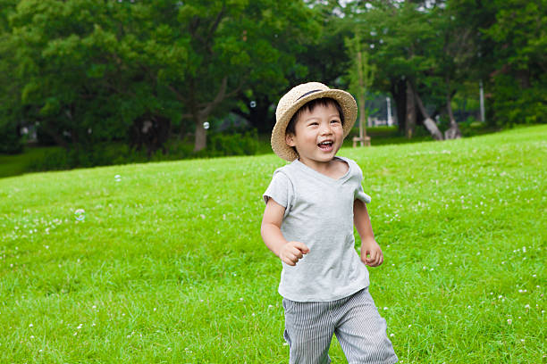 楽しそうに公園を笑いながら走っている少年 - merrily ストックフォトと画像