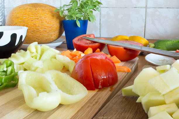 Kitchen full of various vegetables. Pepper, tomatoes sliced and ready to be boiled
